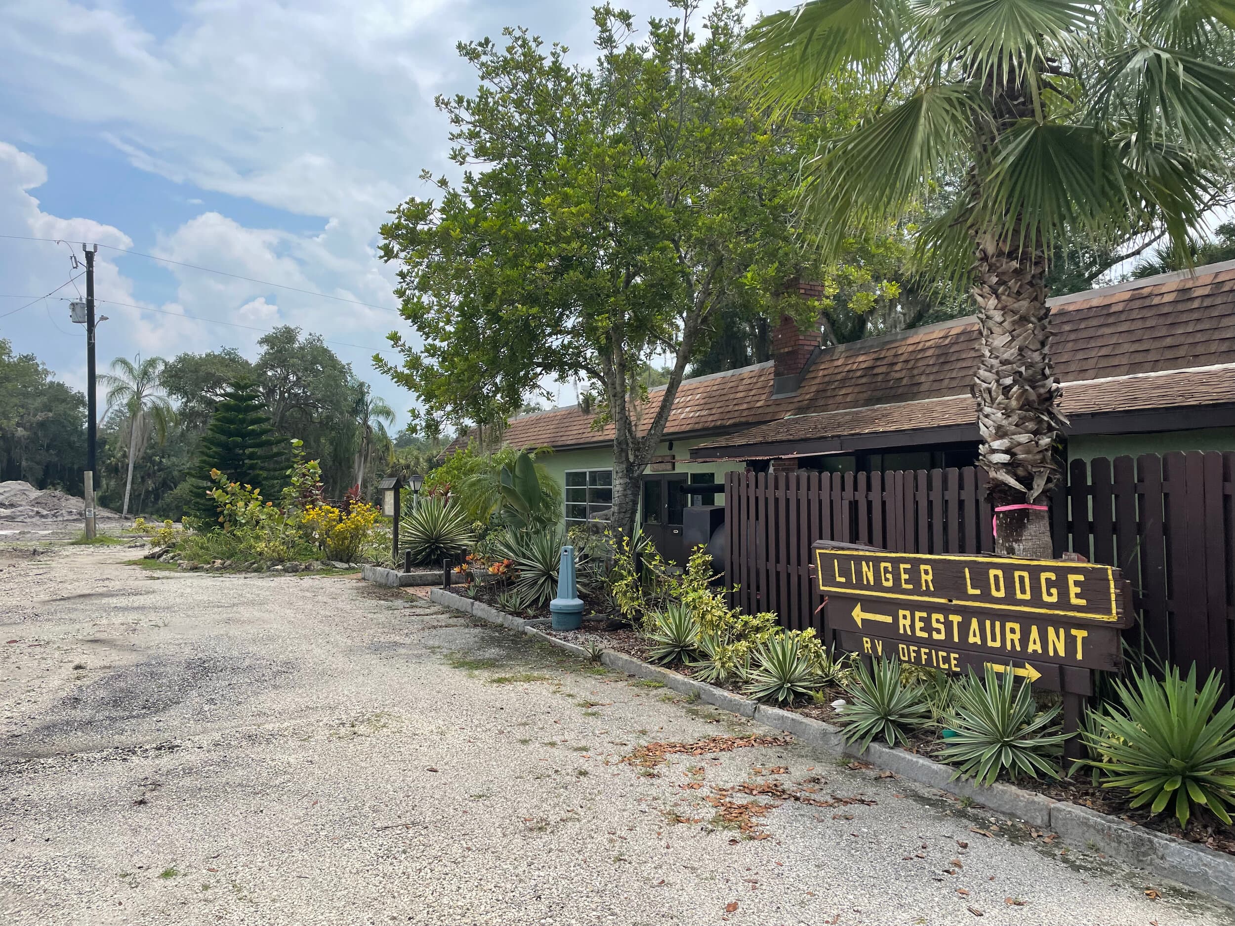 The hand-painted Linger Lodge sign at the turn in, pointing toward the restaurant and the RV office